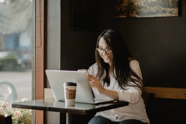 Genç kız öğrenci on-line önünde açık net-kitap oturan akıllı kadın onun ders önce dizüstü bilgisayar üzerinden öğrenme akıllı