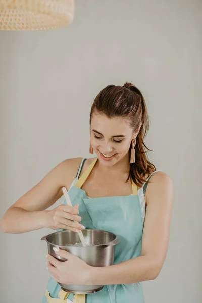 Beautiful woman in apron cooking dessert
