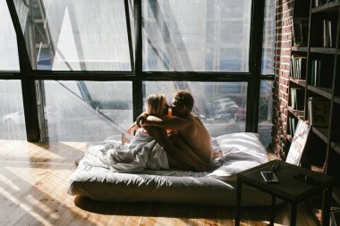 Genç çift yatakta öpüşüyor. 