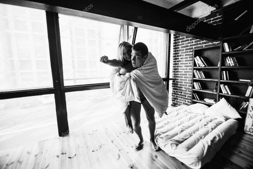 black and white photo of young couple in love posing in appartment 