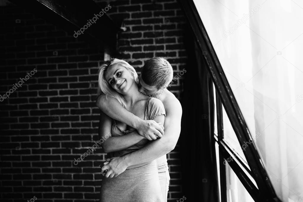 black and white photo of young couple in love posing in appartment 