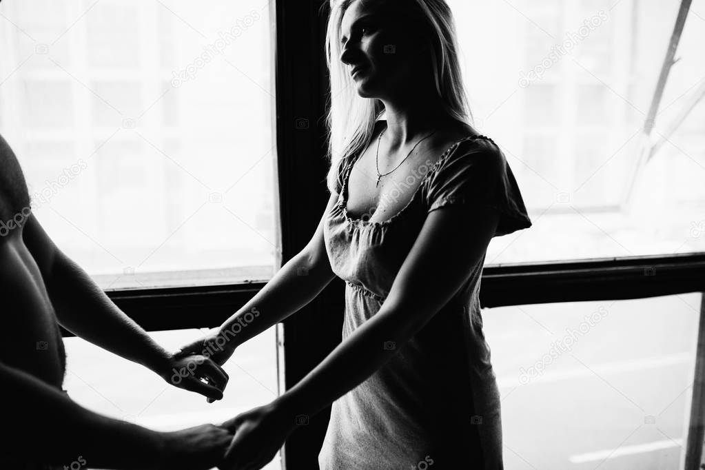 black and white photo of young couple in love posing in appartment 