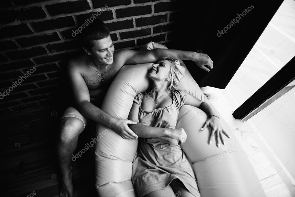 black and white photo of young couple in love posing in bedroom