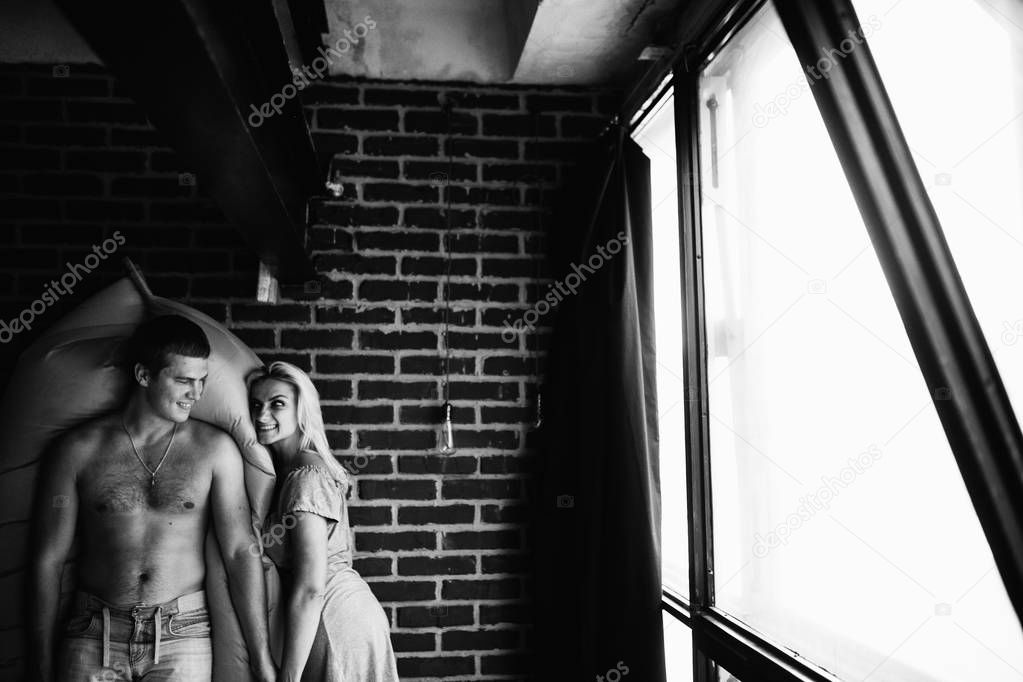 black and white photo of young couple in love posing in bedroom