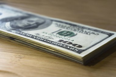 ahşap arka plan üzerinde 100 yeni banknotlar crolled yığını