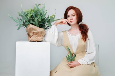 Genç güzel kadın yaratıcı altın makyaj poz çiçekli bir stüdyoda kırmızı saçlı