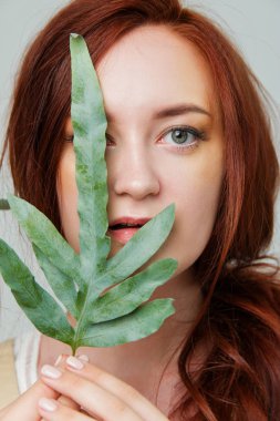 Genç güzel kadın yaratıcı altın makyaj poz çiçekli bir stüdyoda kırmızı saçlı