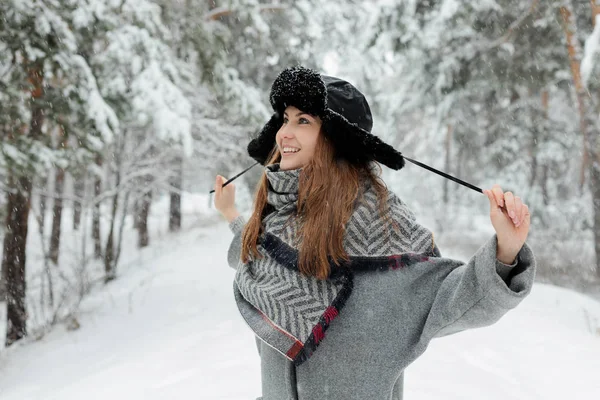Piękna młoda kobieta stojąca wśród ośnieżonych drzew w zimowym lesie i ciesząc się śniegiem. — Zdjęcie stockowe