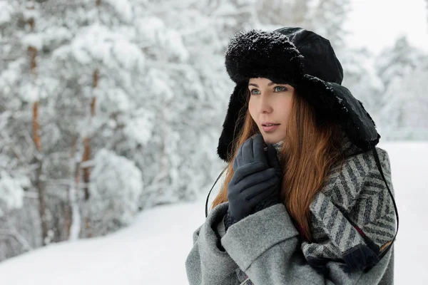 Piękna młoda kobieta stojąca wśród ośnieżonych drzew w zimowym lesie i ciesząc się śniegiem. — Zdjęcie stockowe