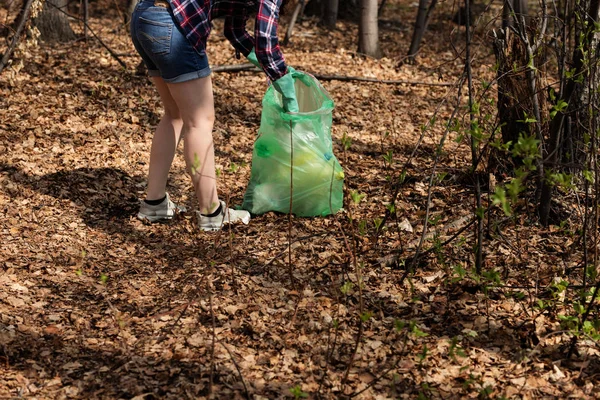 woman picking up dump on dirty forest