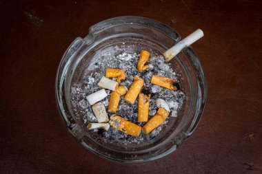 Kahverengi arka plan üzerinde kül tablası sigara izmaritleri