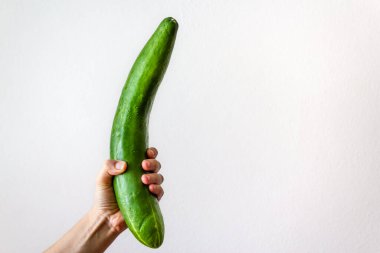 Beyaz arka planda koca bir salatalık tutan bir kadın.