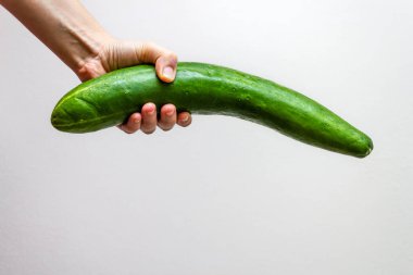 Beyaz arka planda koca bir salatalık tutan bir kadın.