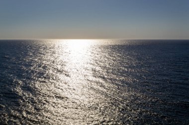 Denizin üzerinde gün batımı, suyun üzerinde ışık yansıması.
