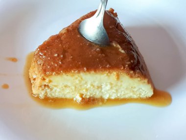 Puding üzerinde beyaz bir tabak ve kaşık şeker şurubu ile lezzetli bir parçası en iyi yan sıkışmış