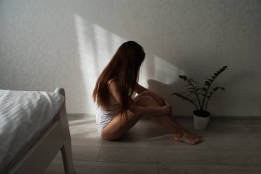Uzun saçlı üzgün bir kız yerde oturuyor..