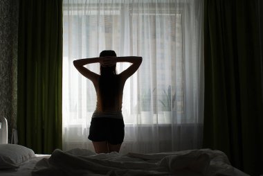 Pencerenin kenarında uzun saçlı bir kızın silueti..