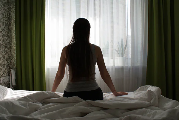 Silhouette Una Ragazza Con Capelli Lunghi Sul Letto Vicino Alla — Foto Stock