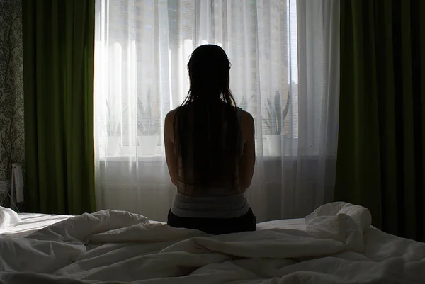 Silhouette Una Ragazza Con Capelli Lunghi Sul Letto Vicino Alla — Foto Stock