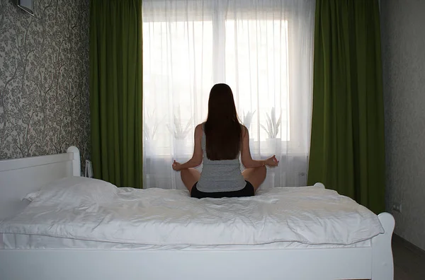 窓際のベッドの上に長い髪を持つ少女のシルエット — ストック写真