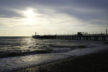 Gün batımı arka planında denizde iskele ve tekneler.