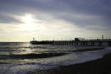 Gün batımı arka planında denizde iskele ve tekneler.