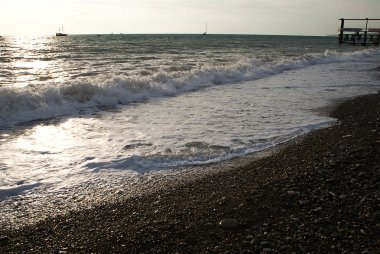 Gün batımı arka planında denizde iskele ve tekneler.