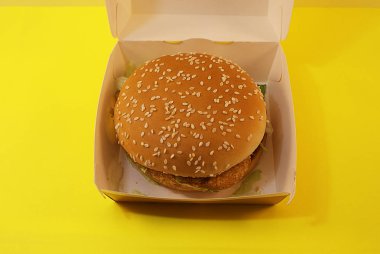 Zararlı burger, sarı arka planda fast food.