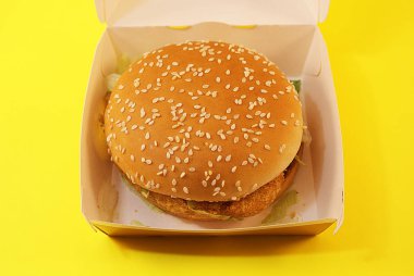 Zararlı burger, sarı arka planda fast food.