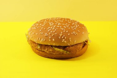Zararlı burger, sarı arka planda fast food.