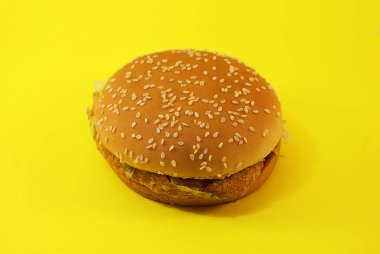 Zararlı burger, sarı arka planda fast food.