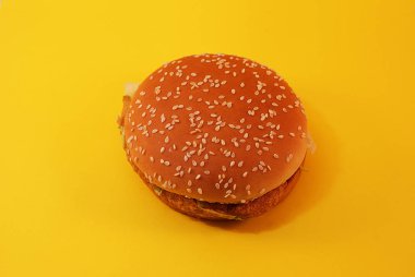 Zararlı burger, sarı arka planda fast food.