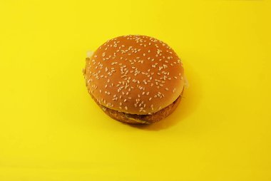 Zararlı burger, sarı arka planda fast food.