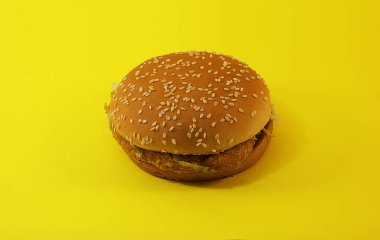 Zararlı burger, sarı arka planda fast food.