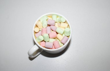 Beyaz bir kupa renkli marshmallow ile kahve bir fincan.