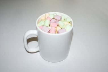 Beyaz bir kupa renkli marshmallow ile kahve bir fincan.