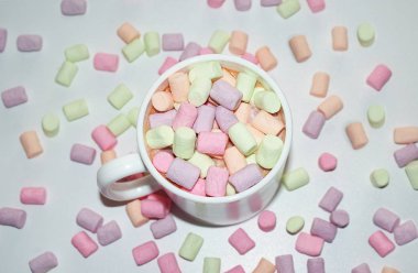 Beyaz bir kupa renkli marshmallow ile kahve bir fincan.