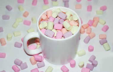Beyaz bir kupa renkli marshmallow ile kahve bir fincan.