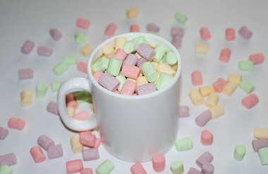 Beyaz bir kupa renkli marshmallow ile kahve bir fincan.