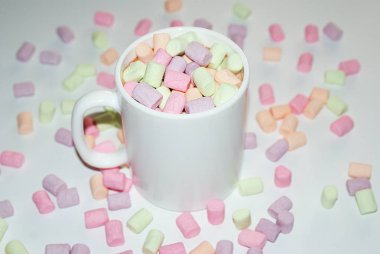 Beyaz bir kupa renkli marshmallow ile kahve bir fincan.