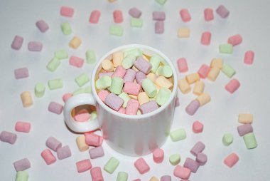 Beyaz bir kupa renkli marshmallow ile kahve bir fincan.