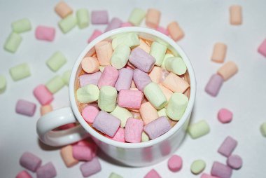 Beyaz bir kupa renkli marshmallow ile kahve bir fincan.