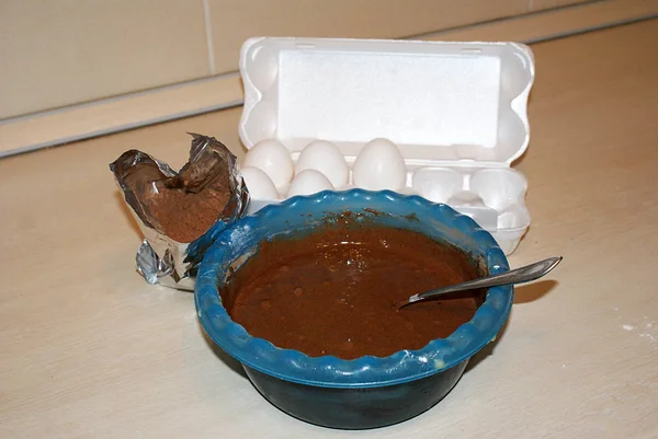 A container with eggs, a mixer and dough.