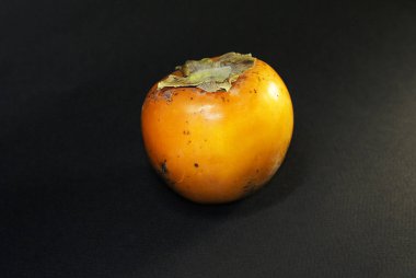 Olgun portakal hurması, siyah bir arka planda izole edilmiş..