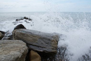 Deniz, dalgalar taşların üzerinde, deniz kıyısında kırılıyor.