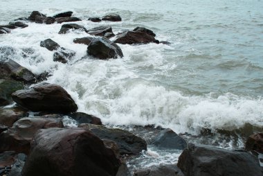 Deniz, dalgalar taşların üzerinde, deniz kıyısında kırılıyor.