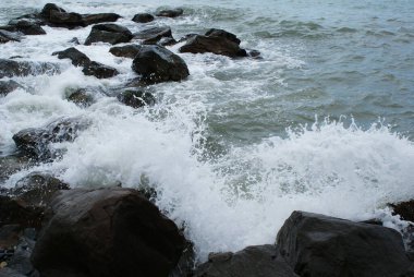 Deniz, dalgalar taşların üzerinde, deniz kıyısında kırılıyor.