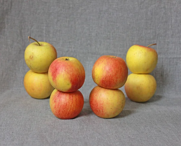 four towers of ripe apples on a gray background
