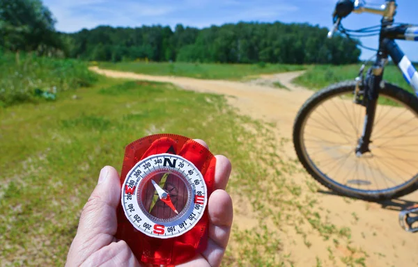 With a compass and a Bicycle front fork. Orientation during a bike ride in rural areas.