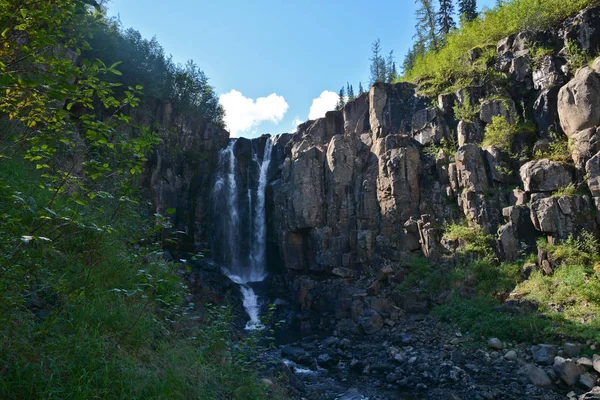 Waterfall in the rocks. Landscape with a waterfall in a mountain gorge on the Putorana plateau.
